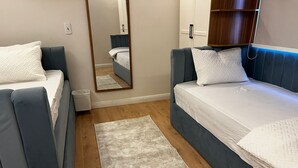 Une chambre avec deux lits, un miroir, une armoire et un radiateur.