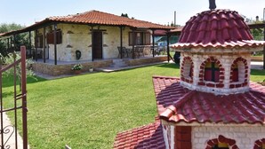 Un bâtiment avec un toit recouvert de tuiles rouges, un petit porche et une croix au sommet.