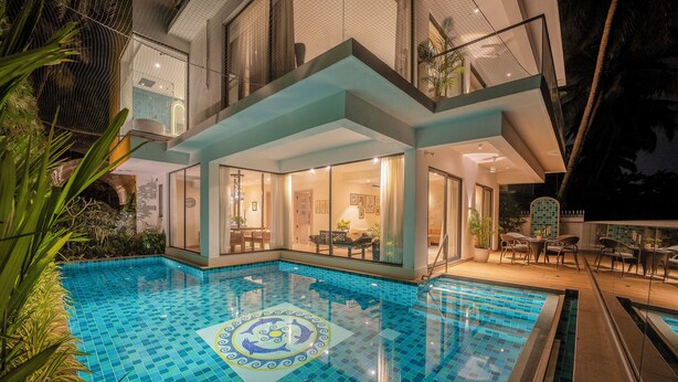 Ein Innenpool mit geometrischem Fliesendesign, einem glasumgebenen Lounge-Bereich und Blick ins Innere.