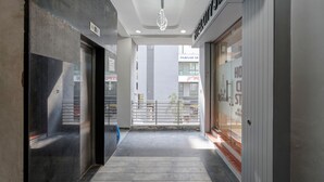 Un pasillo de diseño moderno, con una puerta de cristal a la derecha y una puerta de metal a la izquierda.