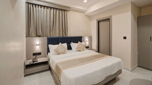 Una habitación de hotel con cama, mesitas de noche, un armario y una ventana con cortinas.