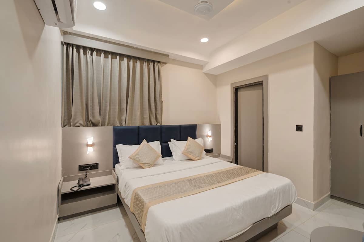 A hotel room with a bed, bedside tables, a wardrobe, and a window with curtains.