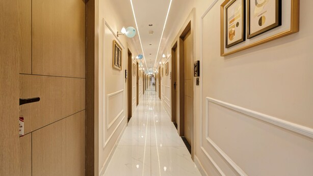 Un pasillo de hotel con puertas de madera, obras de arte enmarcadas y un suelo pulido.