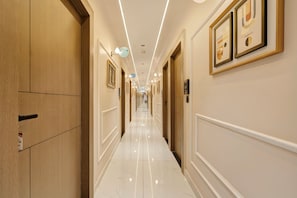 Un pasillo de hotel con puertas de madera, obras de arte enmarcadas y un suelo pulido.