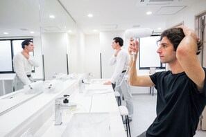 A modern bathroom with a large mirror, multiple sinks, and a hairdryer. - Grand Hostel LDK Osaka Shinsekai - Hostel (Osaka)