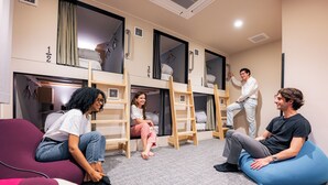A dormitory room with bunk beds, a ladder, and a person standing on the top bunk. - Grand Hostel LDK Osaka Shinsekai - Hostel (Osaka)