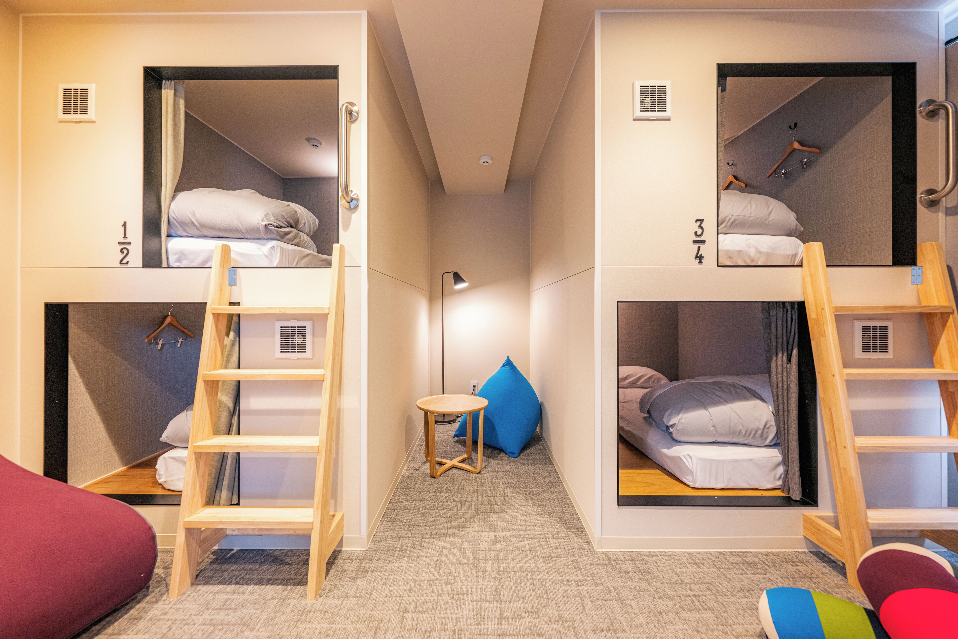 Une chambre de dortoir avec des lits superposés, une petite table et une échelle.