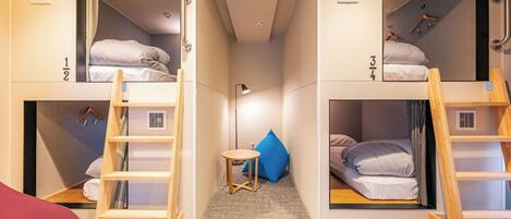 Une chambre de dortoir avec des lits superposés, une petite table et une échelle.