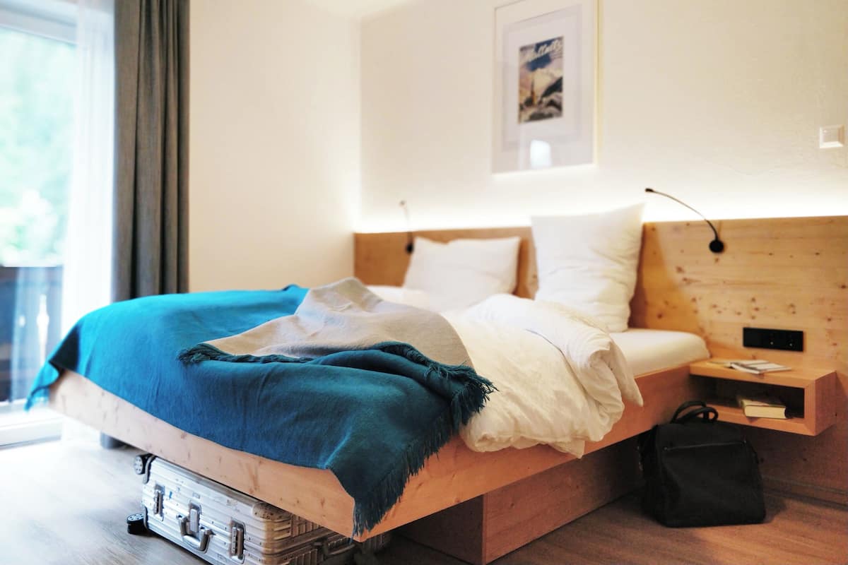 A bed with a blue blanket, white pillows, and a wooden headboard.