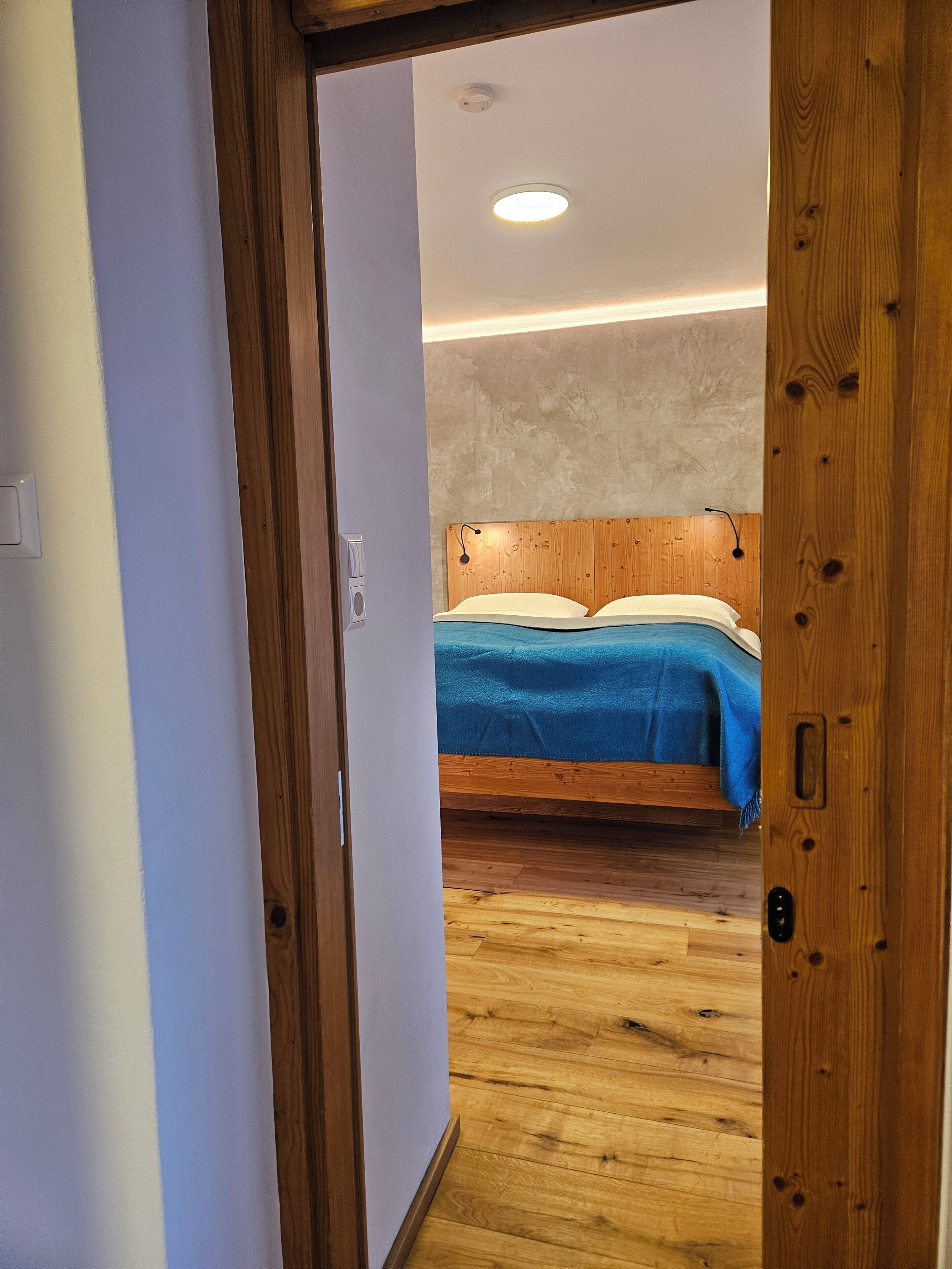 Ein Schlafzimmer mit einem hölzernen Kopfende, einem Bett mit blauer Bettwäsche und einem Holzboden.