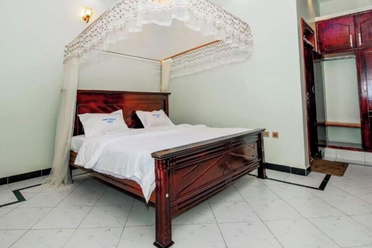 A bed with a canopy, a wardrobe, and a tiled floor.