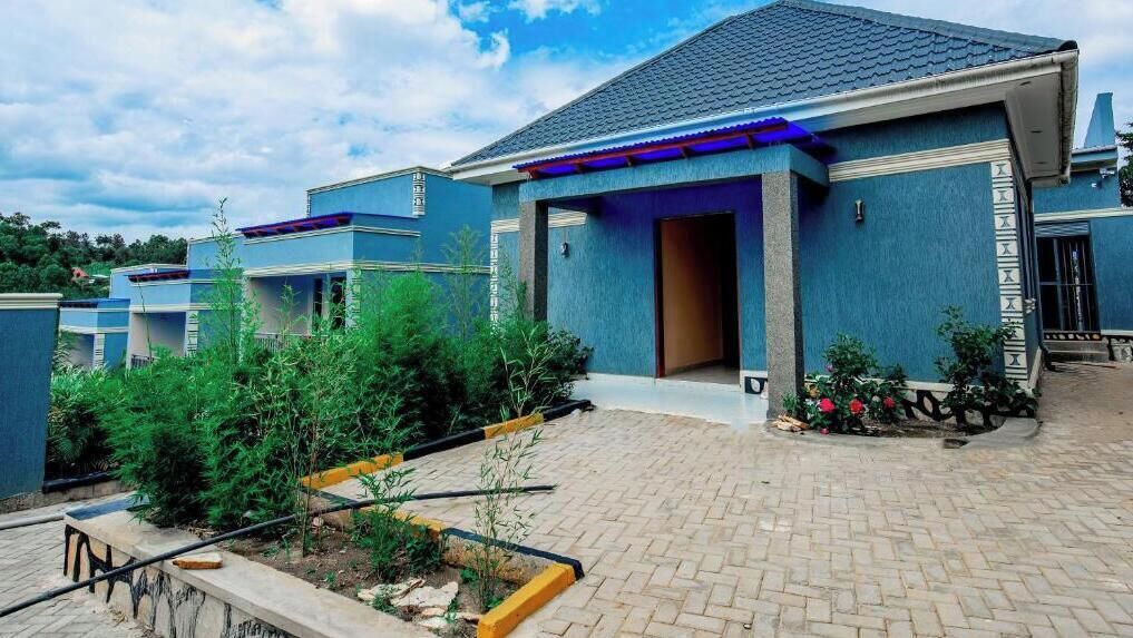 A modern building with a blue exterior, a paved entrance, and a landscaped garden area.