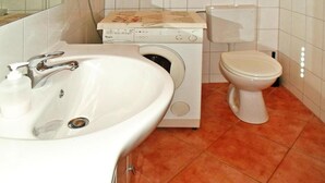 Et badeværelse med vask, vaskemaskine og toilet.