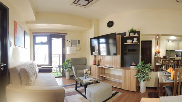 A modern living room with a sofa, a coffee table, a TV, and a dining area with a table and chairs.