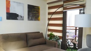 A living room with a sofa, a floor lamp, and two abstract paintings on the wall.