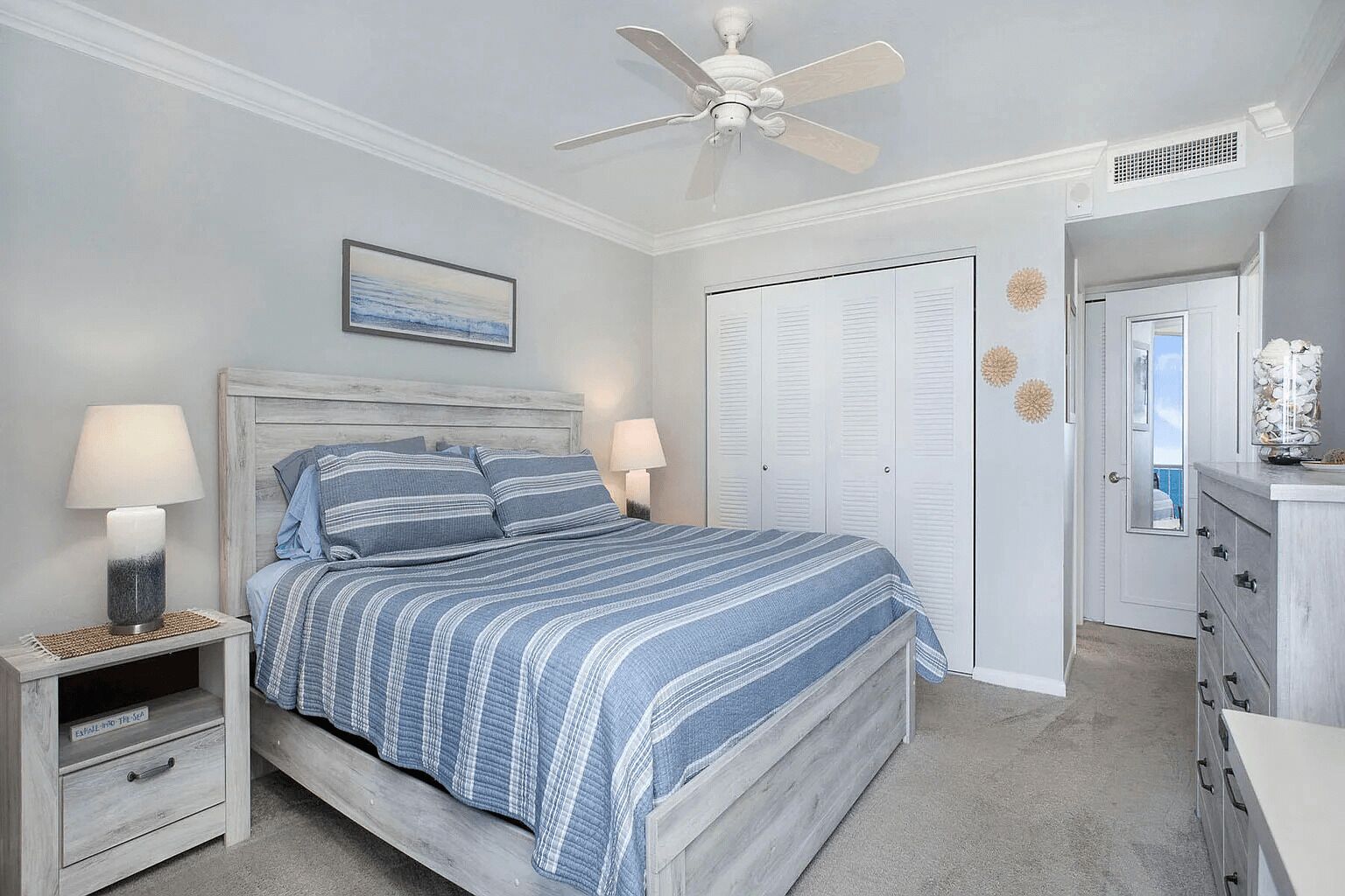 A bedroom with a bed, nightstands, a ceiling fan, a wardrobe, and a dresser.