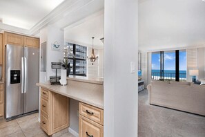Een moderne keuken met roestvrijstalen apparatuur, houten kastjes en een groot raam met uitzicht op de oceaan.