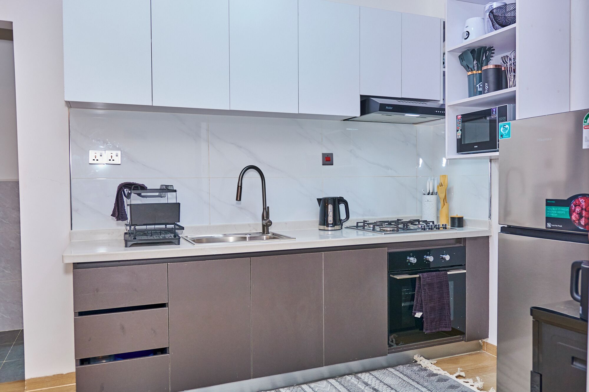 A modern kitchen with a sink, stove, and microwave.