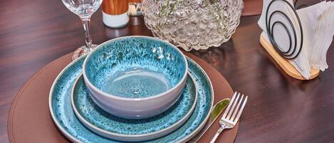 A dining table set with a blue bowl, a wine glass, and a fork.