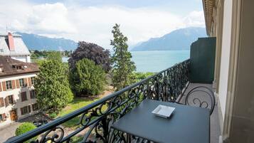 A balcony with a table and a view of a lake and mountains.