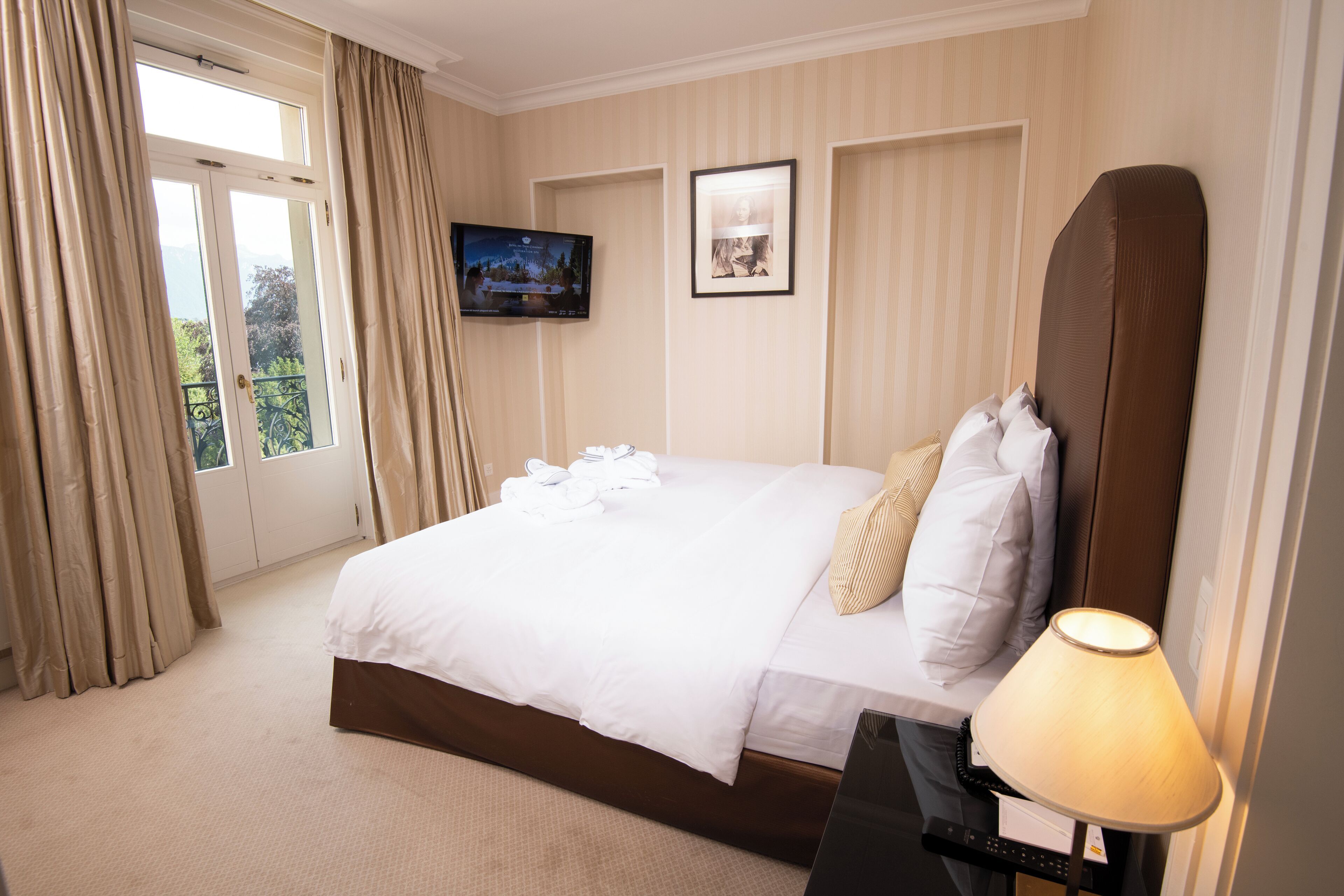 Una habitación de hotel con cama, televisión, un cuadro enmarcado y una lámpara.