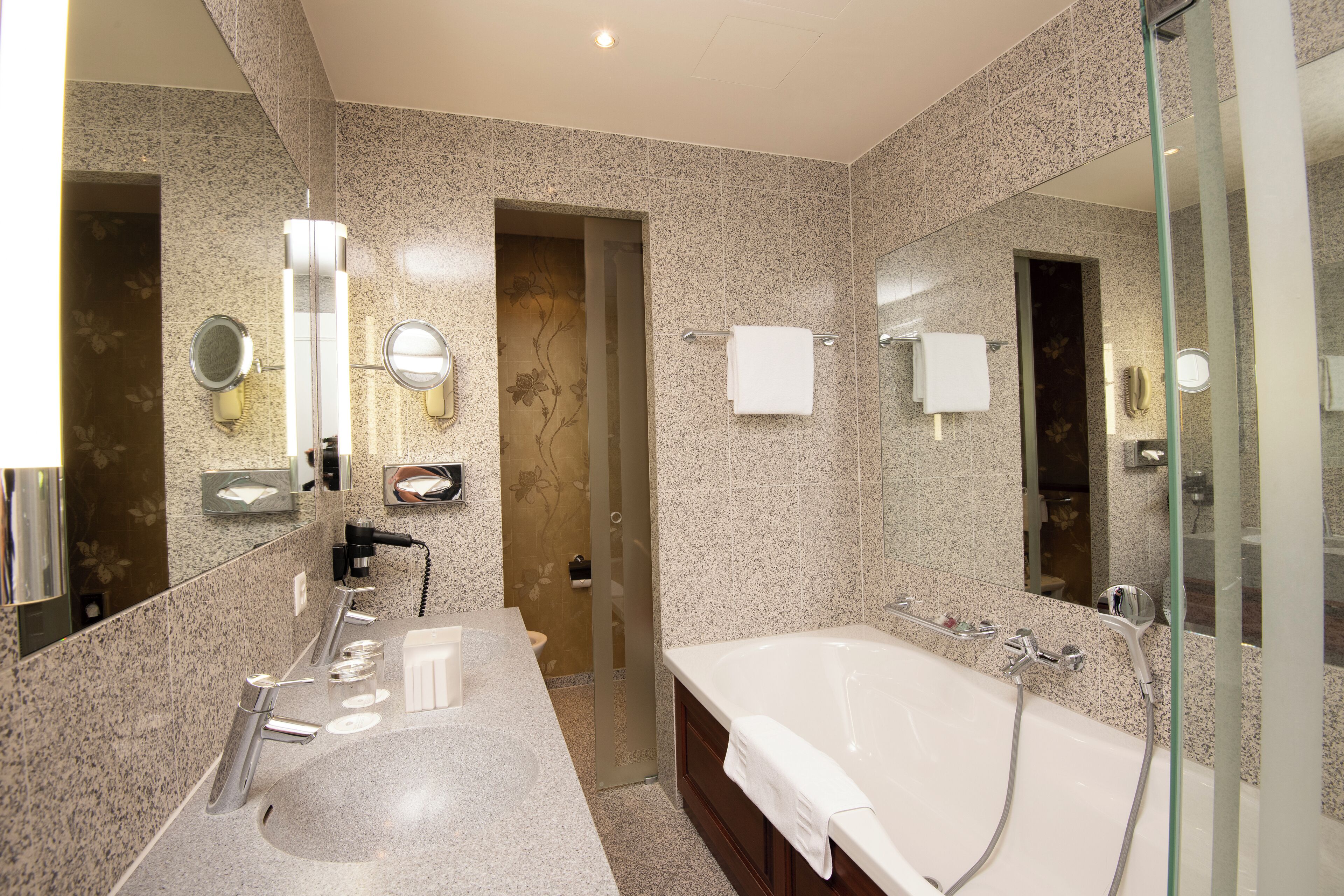 A modern bathroom with a large bathtub, dual sinks, and a glass shower enclosure.