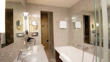 A modern bathroom with a large bathtub, dual sinks, and a glass shower enclosure.