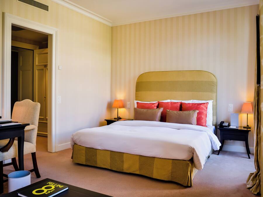 A hotel room with a bed, bedside tables, a chair, and a desk.