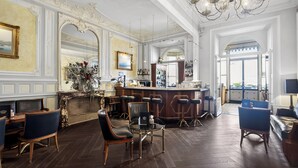 Un espace bar doté d’un comptoir haut, de plusieurs tabourets et d’un coin salon avec des chaises et une table.