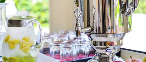 A silver samovar on a table near a window with a view of greenery.