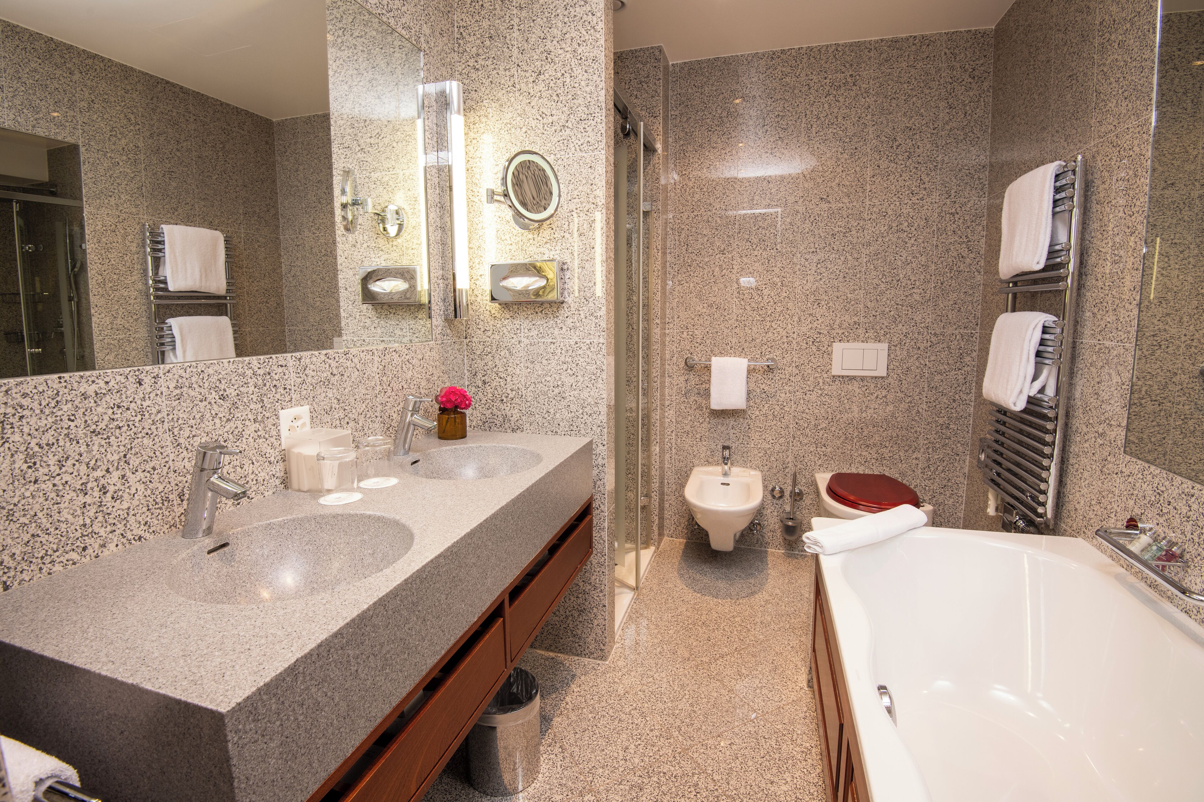 Ein modernes Badezimmer mit Granit-Arbeitsplatten, einem Bidet, einer Toilette und einer Badewanne.