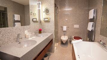 Ein modernes Badezimmer mit Granit-Arbeitsplatten, einem Bidet, einer Toilette und einer Badewanne.