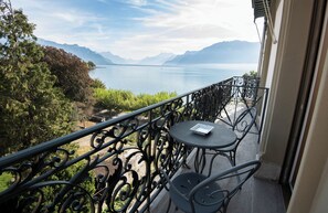 Un balcon avec vue sur un lac et des montagnes, une table et des chaises.