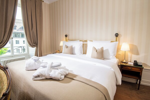 Une chambre d’hôtel avec un lit, deux lampes de chevet, une table de chevet avec un téléphone et une fenêtre avec des rideaux.