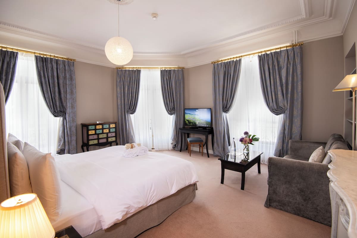 Une chambre d’hôtel avec un grand lit, un bureau, une chaise et un téléviseur.