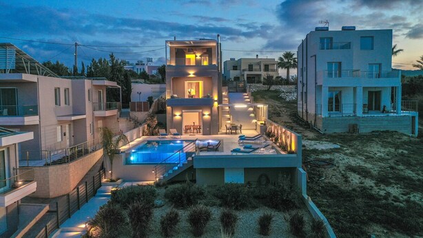 Un moderno edificio residenziale a più piani con piscina, area salotto all'aperto e ingresso ben illuminato.