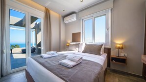 Una camera d'albergo con un letto, due abat-jour, una finestra, un condizionatore e vista sul mare.