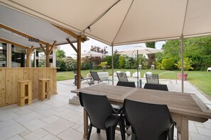 Une terrasse extérieure avec une table et des chaises en bois, un coin bar et des parasols.