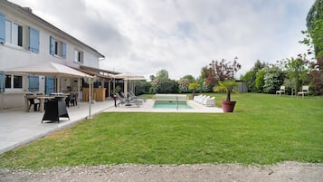 Een gebouw met een overdekt terras, een zwembad en een verzorgd gazon.