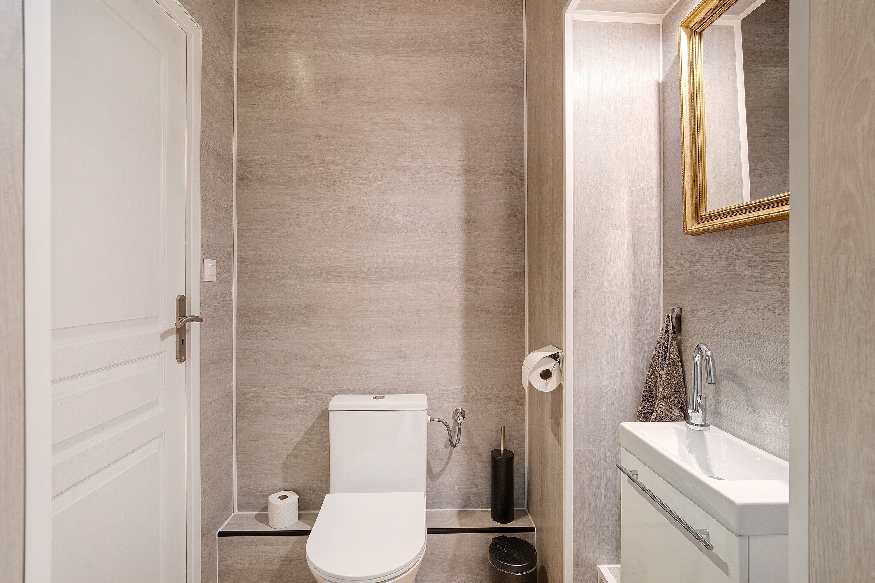 A bathroom with a toilet, sink, and mirror.
