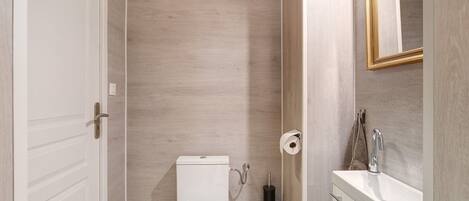 A bathroom with a toilet, sink, and mirror.