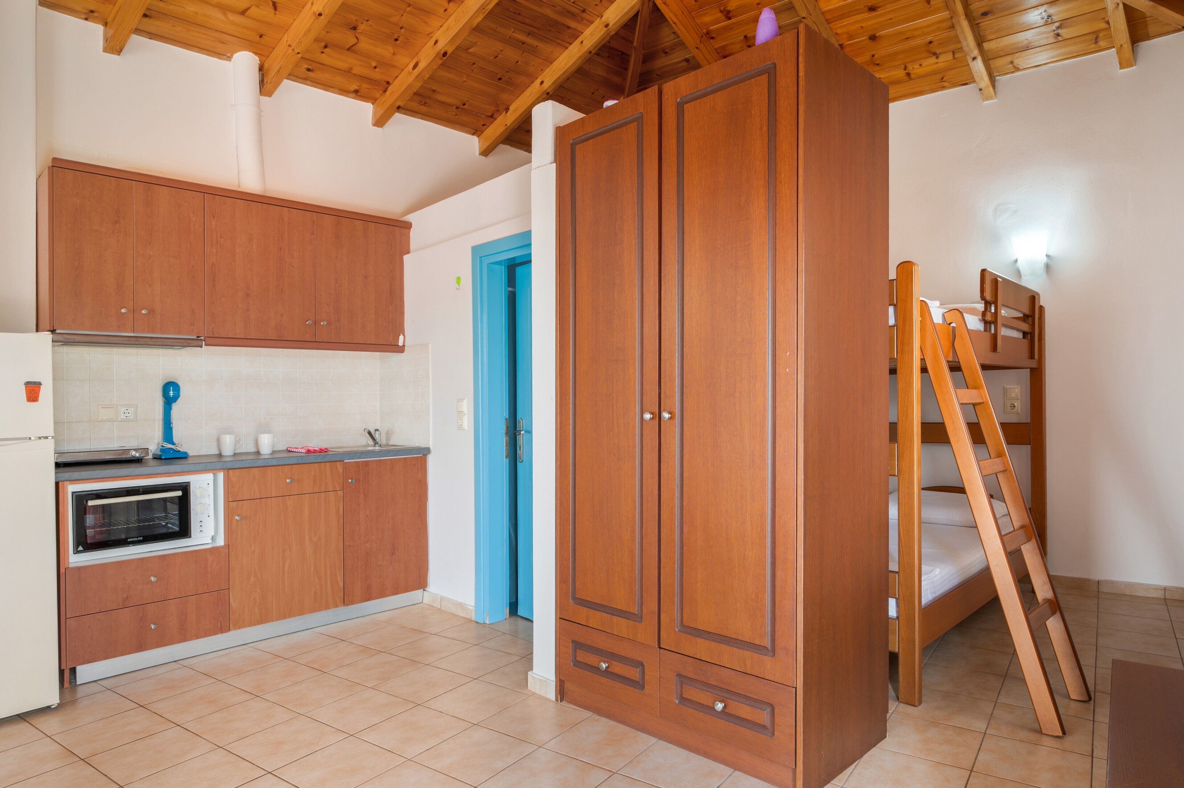 A kitchen with wooden cabinets, a built-in oven, and a blue door.
