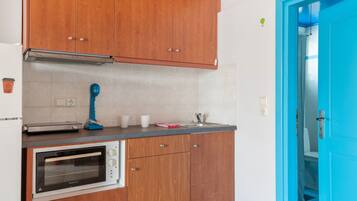 A kitchen with wooden cabinets, a built-in oven, a blue hairdryer, and a blue door.