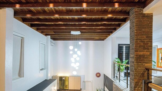 A modern interior with exposed wooden beams, a staircase, and a hanging light fixture. - Short Stays By CW (Lagos)