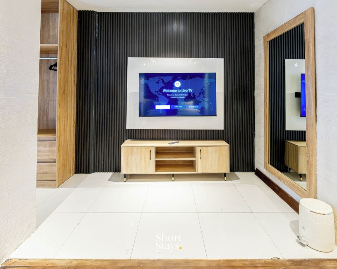 A modern living room with a mounted TV, wooden console, and a large mirror.