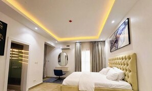 Una habitación de hotel moderna con una cama grande, un escritorio, una silla, un espejo y un cuadro en la pared.