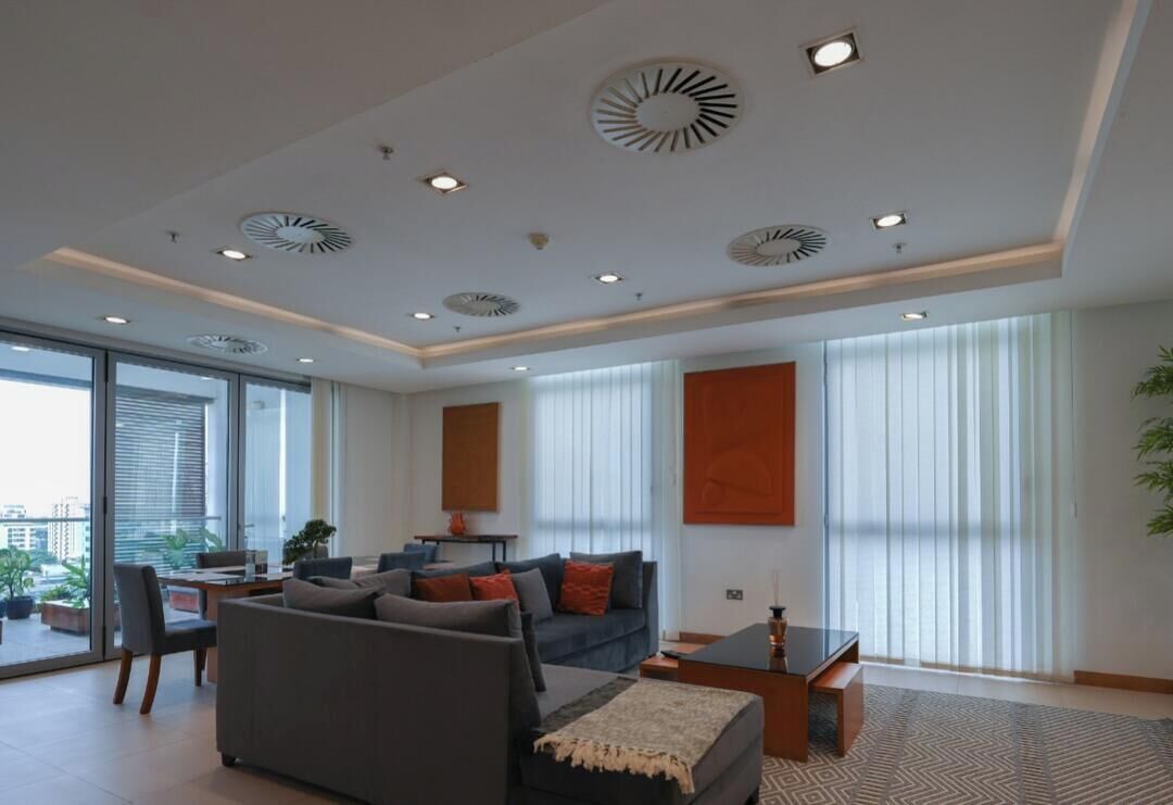 A modern living room with a sofa, coffee table, and a dining area with a table and chairs.