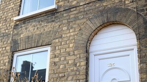 Ein Backsteinhaus mit einer weißen Tür, auf der '125' steht, und einem Fenster.