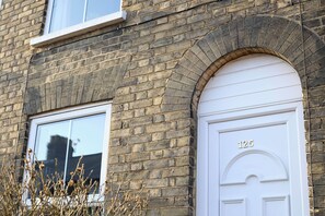 Un bâtiment en briques avec une porte blanche portant le numéro « 125 » et une fenêtre.