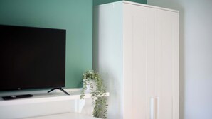 Ein Zimmer mit Fernseher auf einem Schrank, einem Schrank und einer Pflanze.